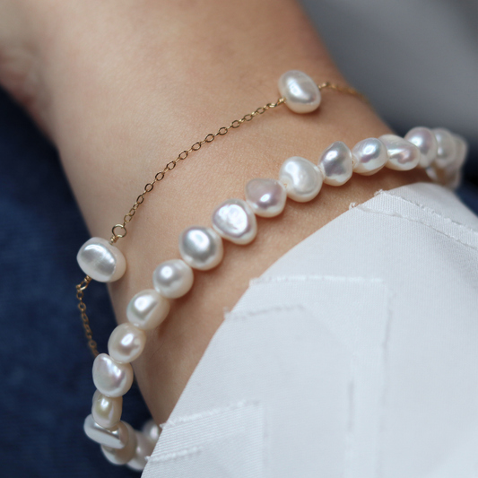 A stunning baroque pearl bracelet featured on a gold chain, emphasizing the elegance of the pearls against the gold backdrop.