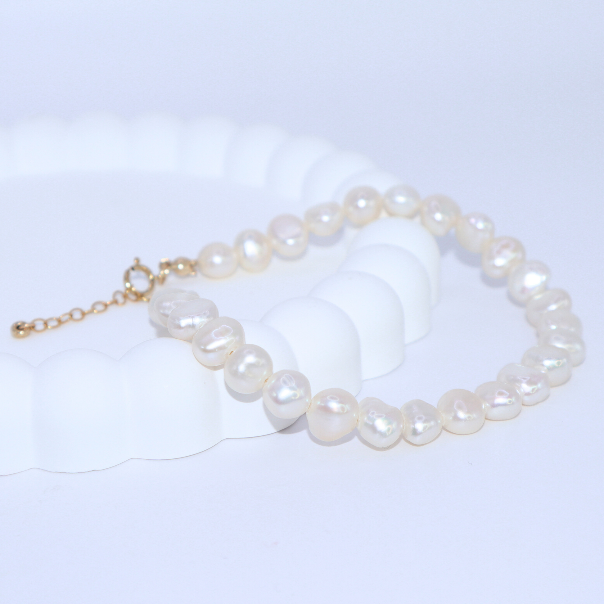 A stylish white baroque pearl bracelet adorned with a gold extension chain, highlighting a refined and contemporary aesthetic.
