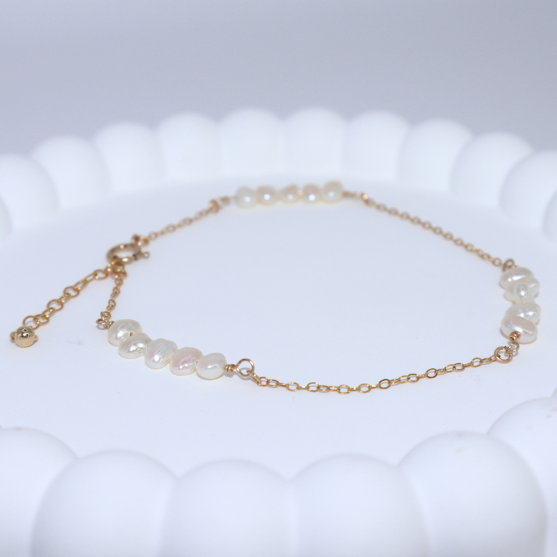 A delicate chain bracelet featuring clusters of four small, lustrous pearls elegantly arranged along its length.