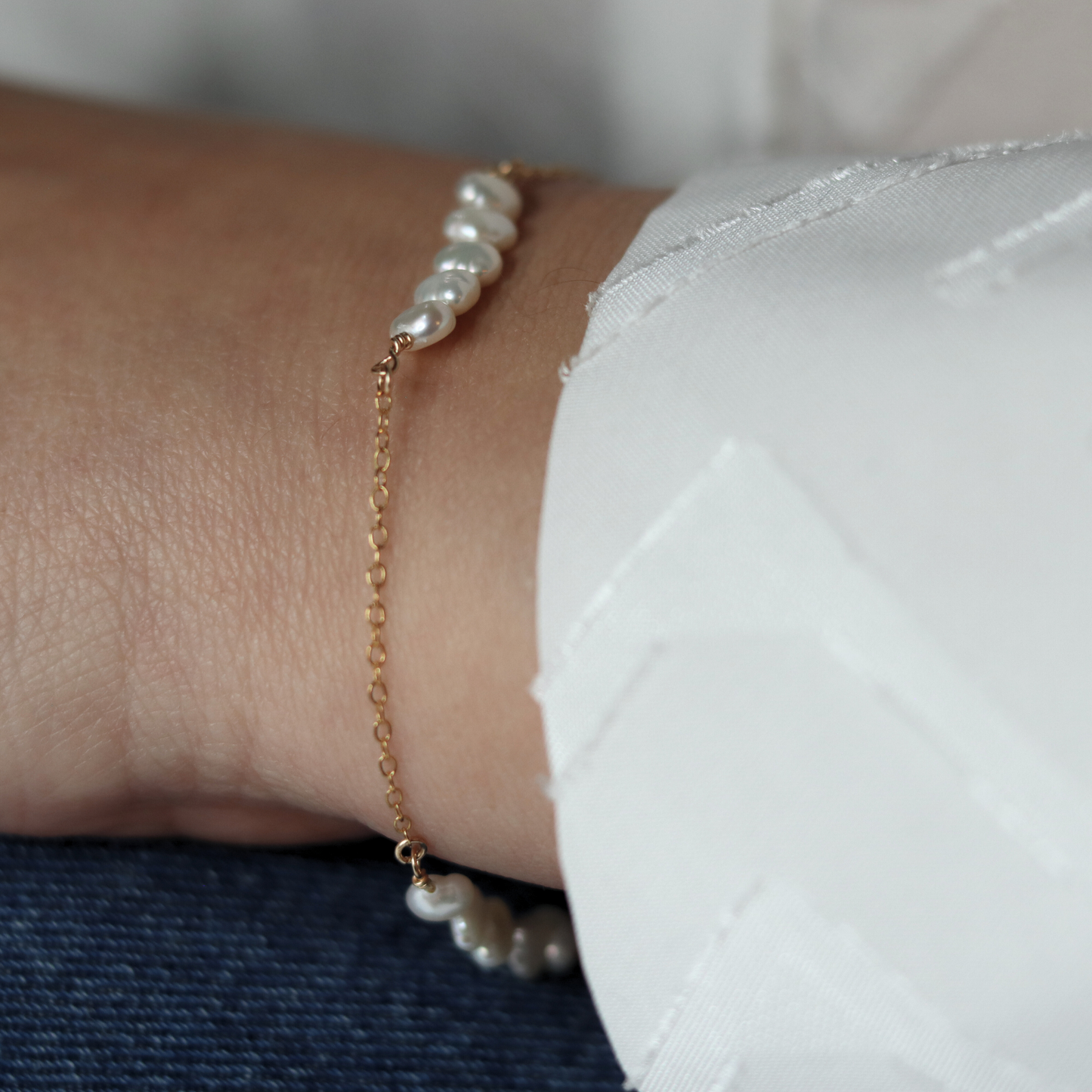 A delicate chain bracelet featuring clusters of four small, lustrous pearls elegantly arranged along its length.