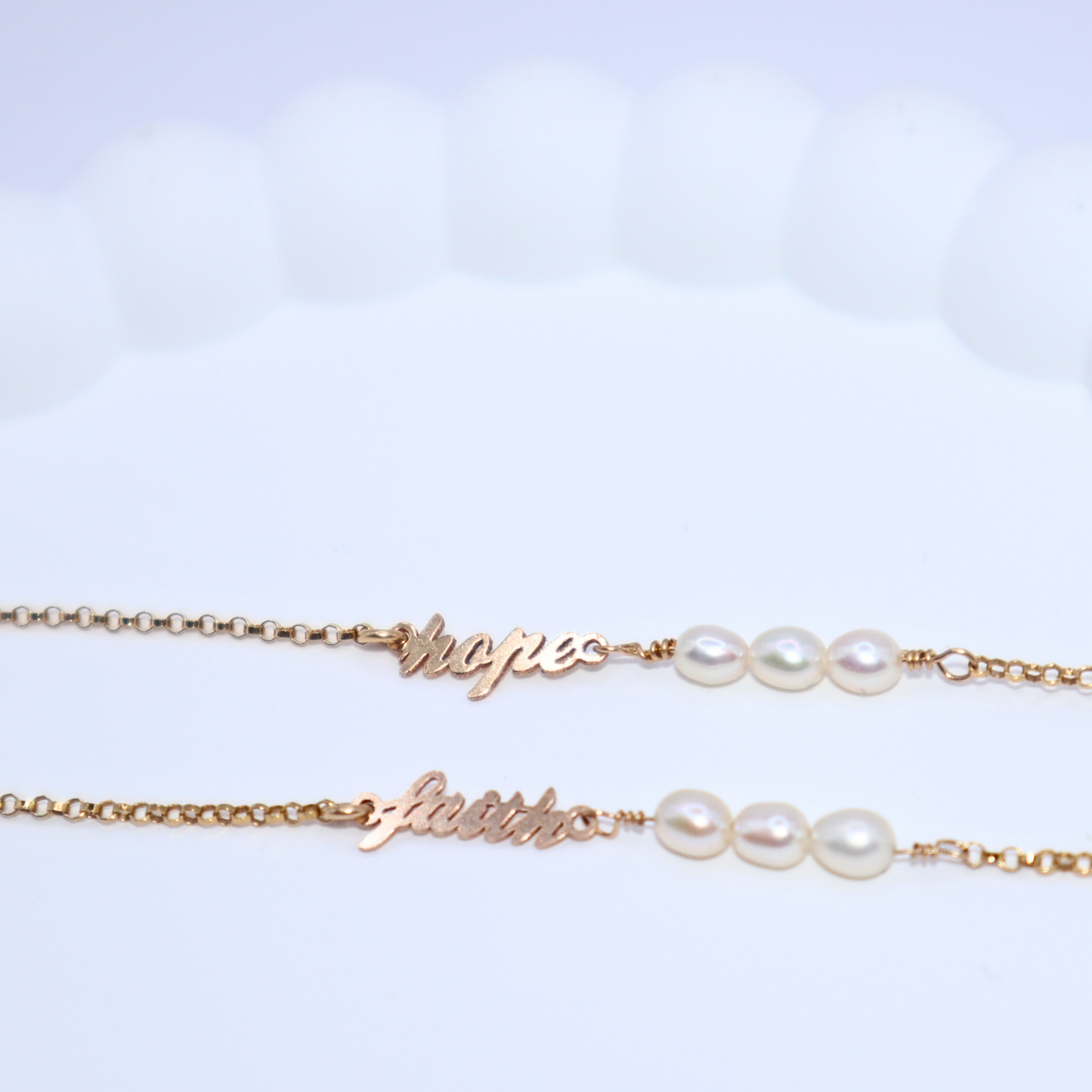 a dainty chain adorned with three small rice pearls and the word "faith"