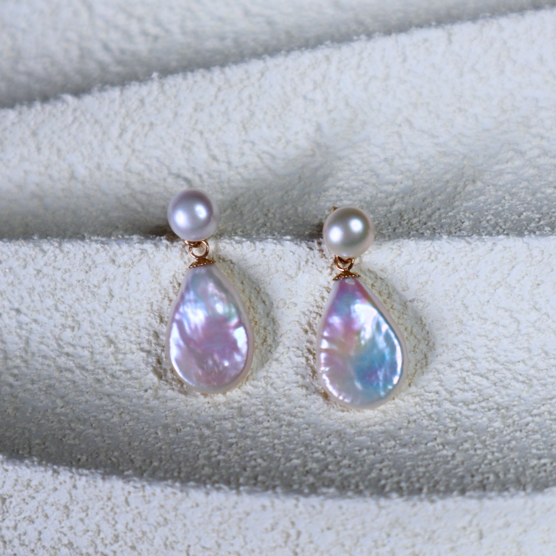 Pearl drop 2 in 1 earrings with teardrop-shaped pearls on a textured white surface