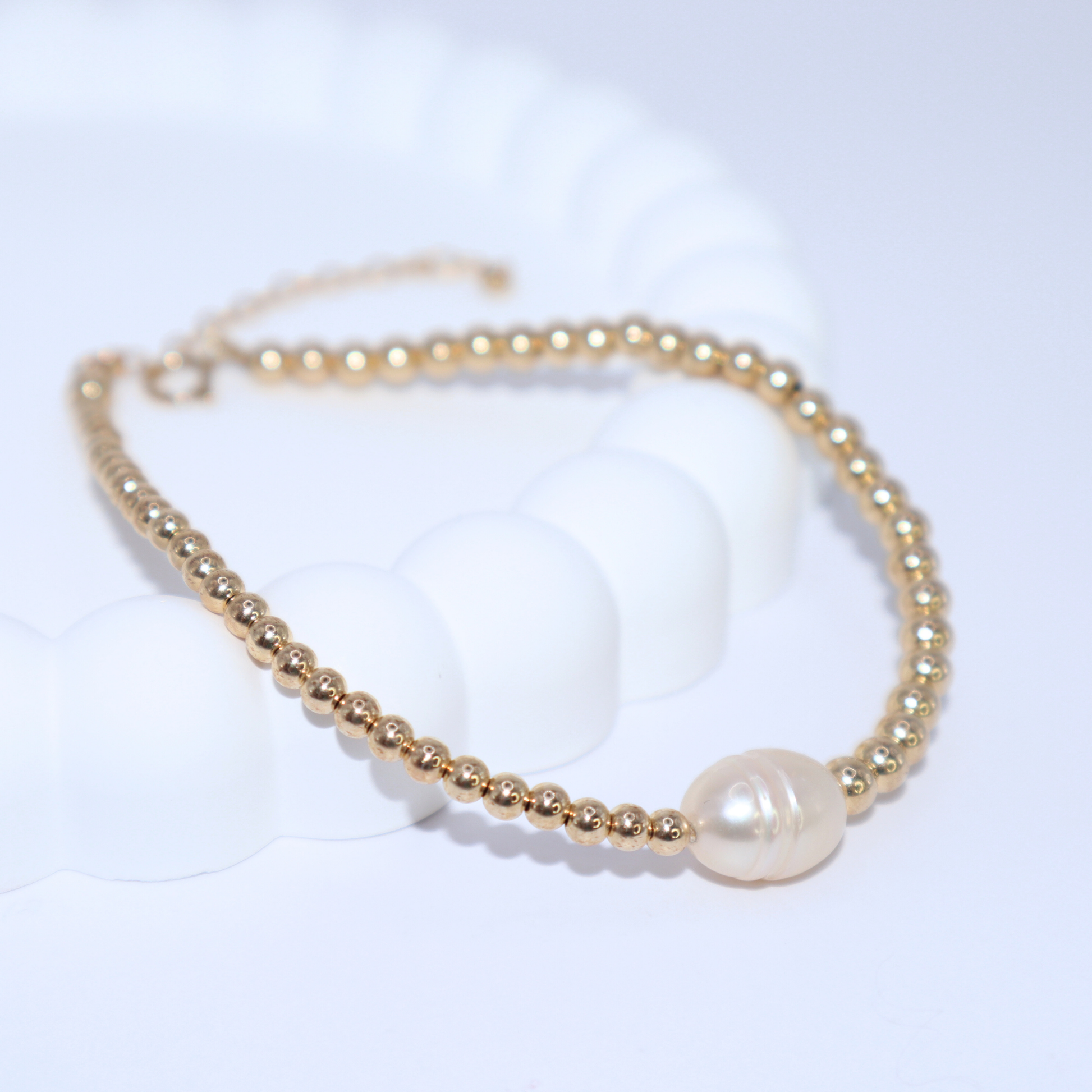 An exquisite gold beads bracelet with a prominent pearl, embodying elegance and timeless beauty.