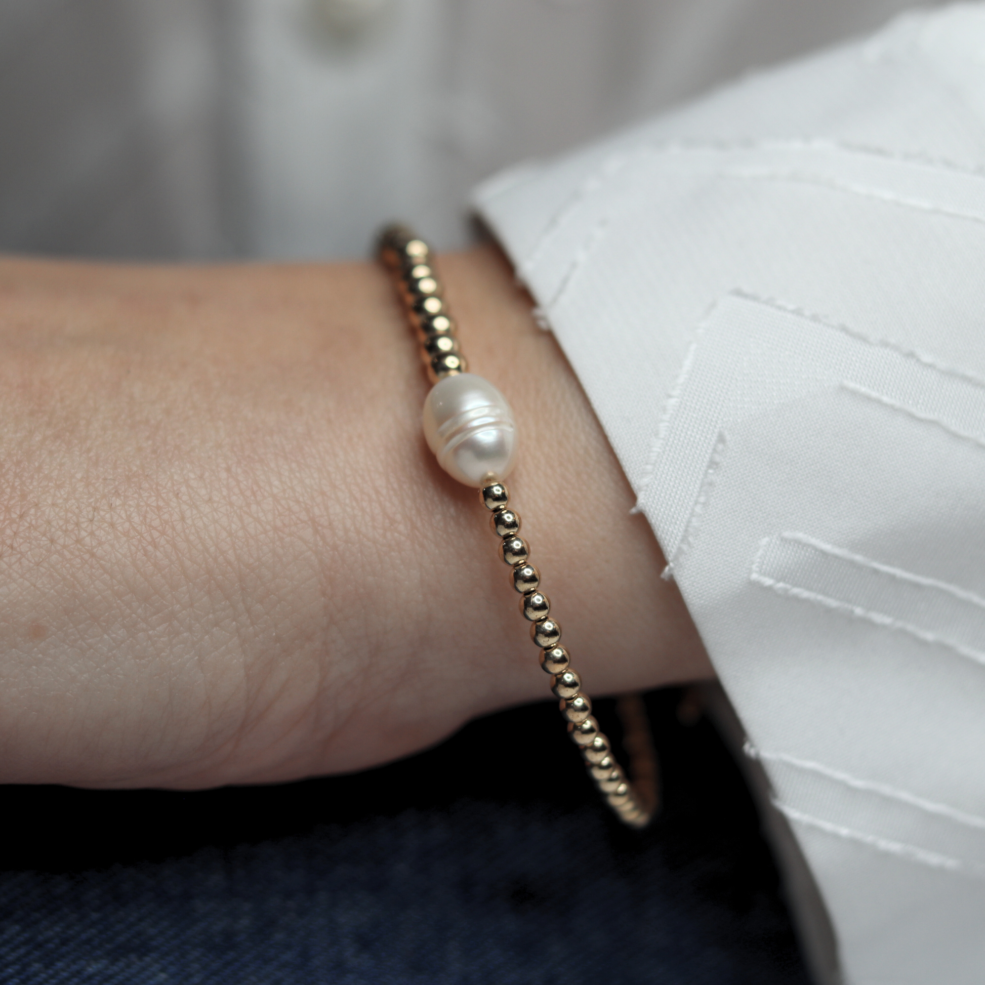 An exquisite gold beads bracelet with a prominent pearl, embodying elegance and timeless beauty.