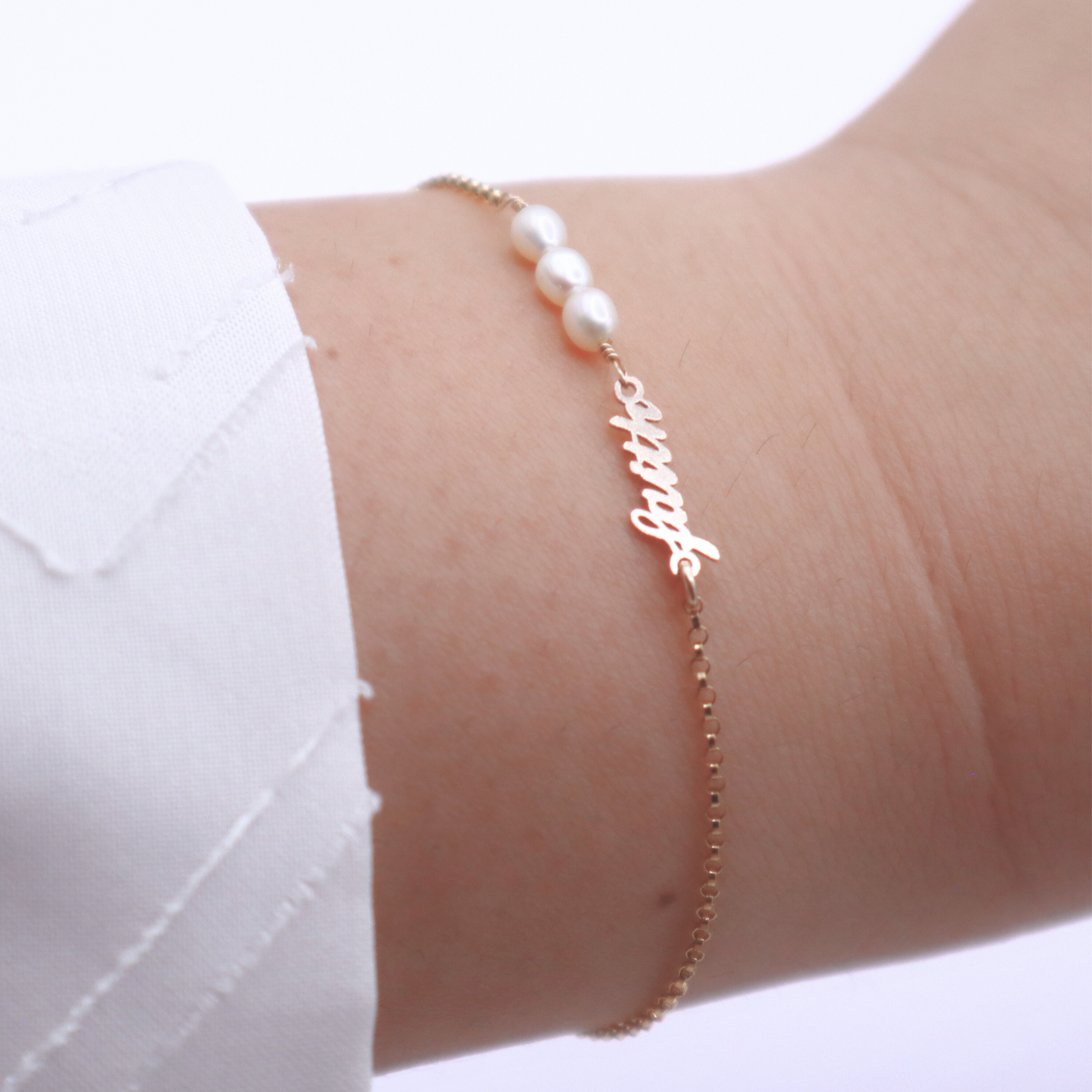 a dainty chain adorned with three small rice pearls and the word "faith"