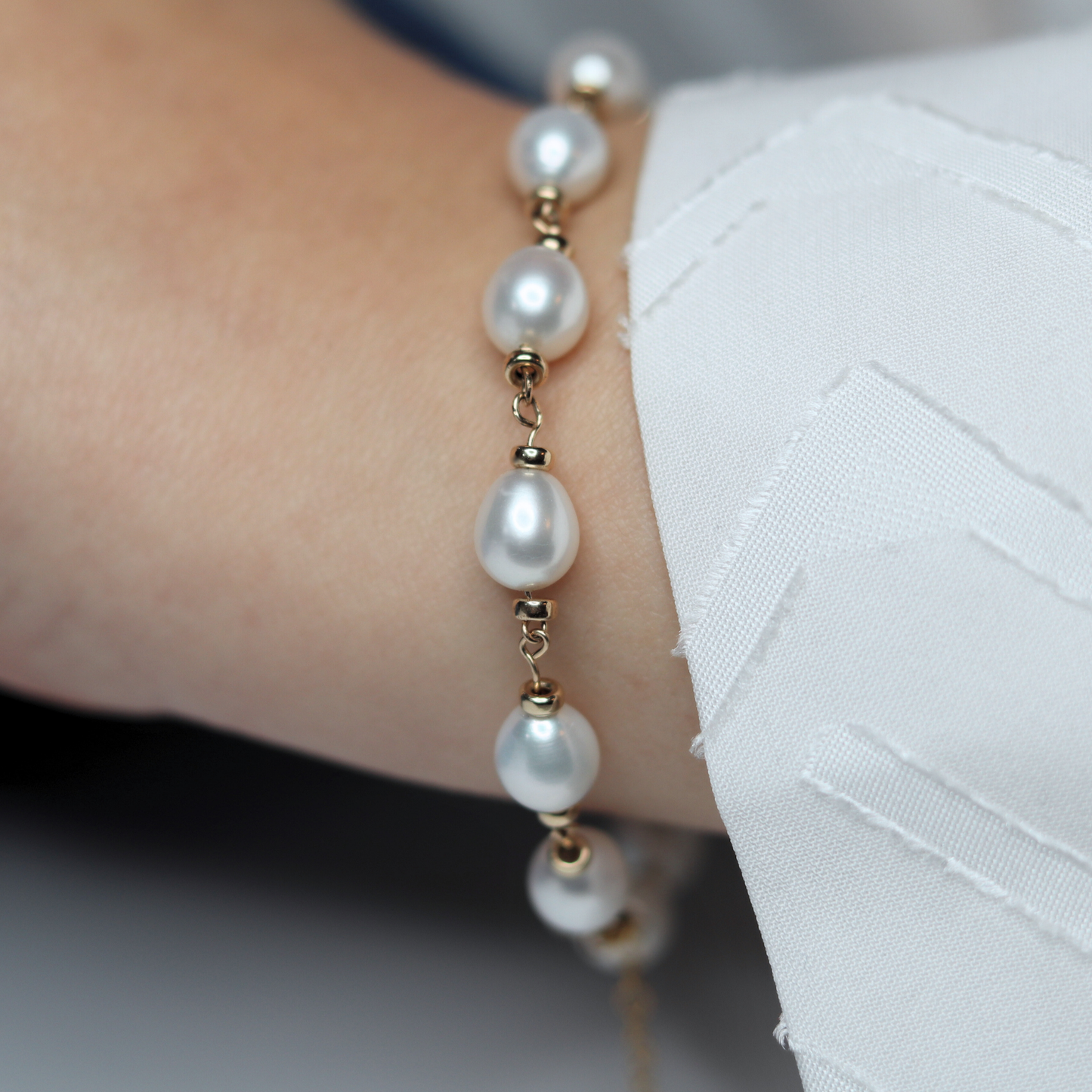A stunning bracelet featuring lustrous white pearls and gold rondelle beads intertwined with a luxurious gold chain, perfect for any occasion.