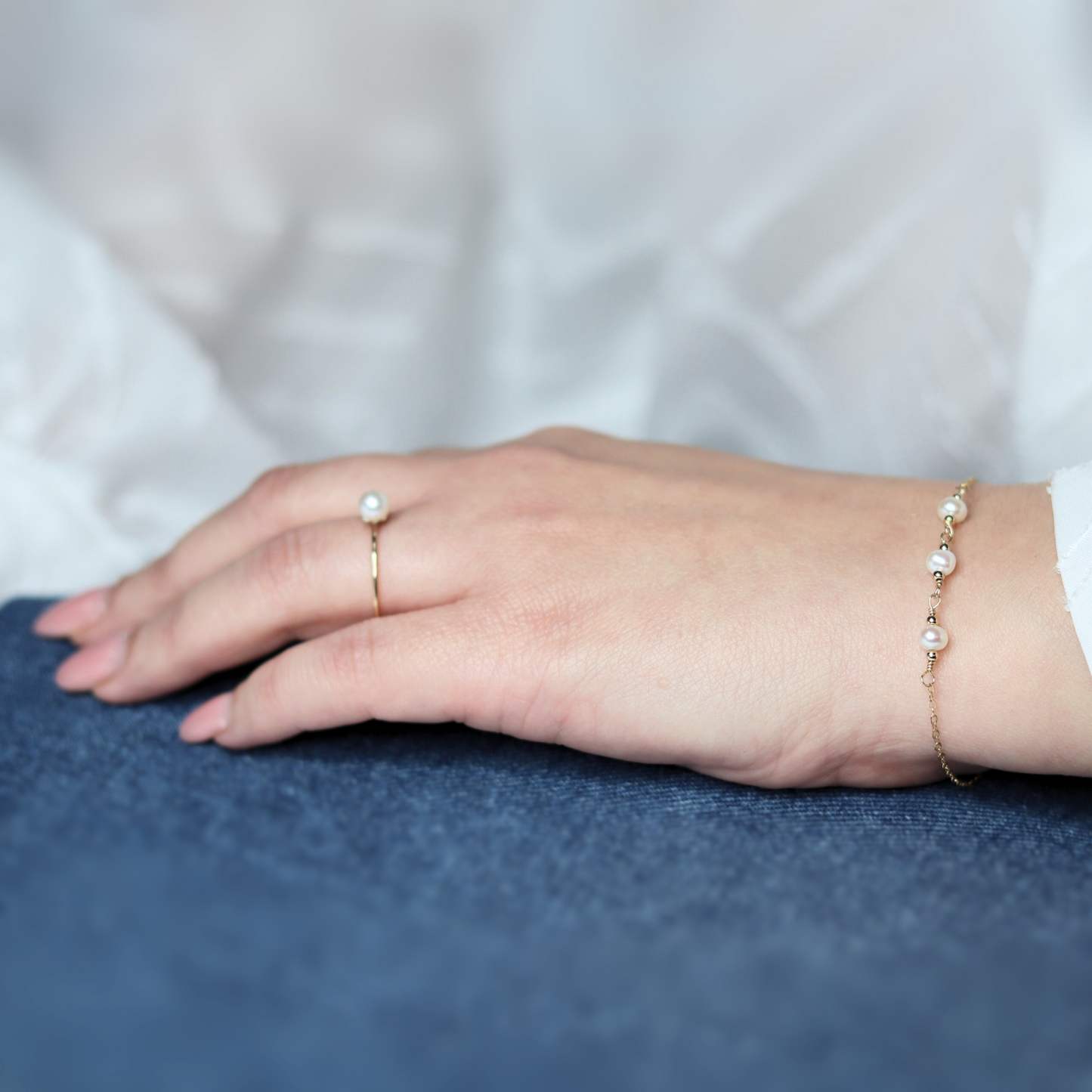 A gold chain bracelet adorned with three elegant pearls surrounded by gold beads, showcasing a blend of luxury and sophistication.