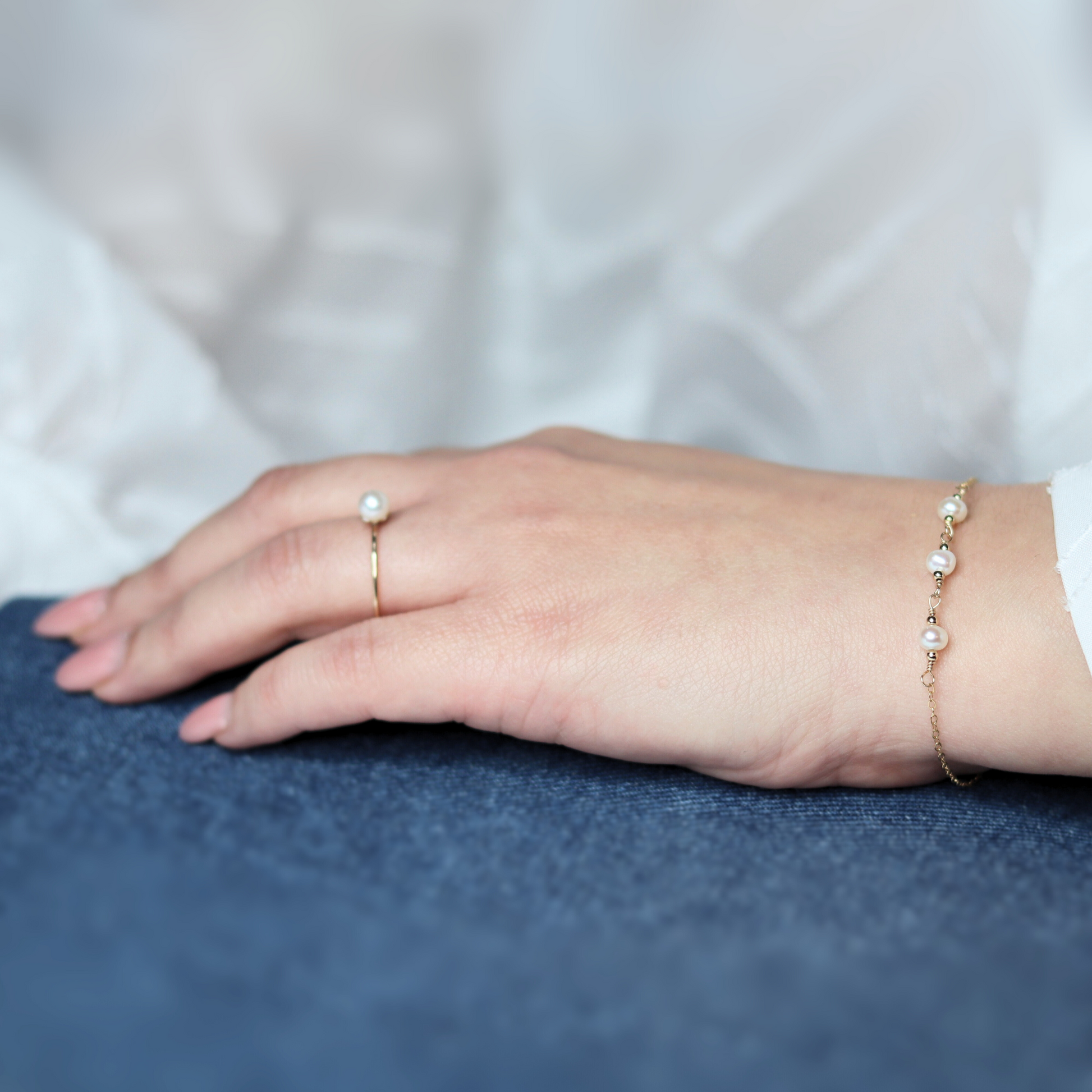 A gold chain bracelet adorned with three elegant pearls surrounded by gold beads, showcasing a blend of luxury and sophistication.