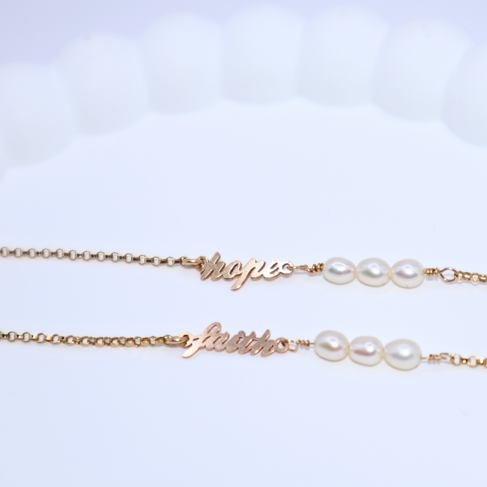 a dainty chain adorned with three small rice pearls and the word "hope".