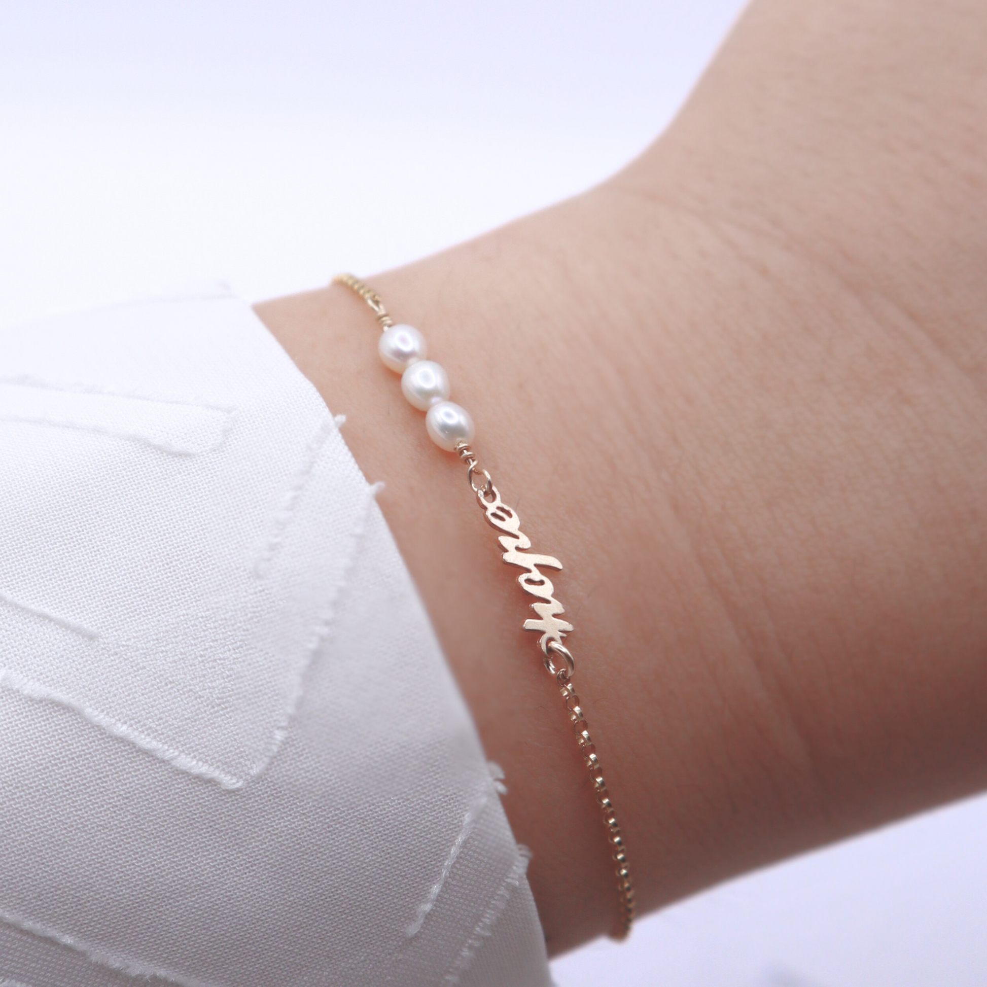 a dainty chain adorned with three small rice pearls and the word "hope".