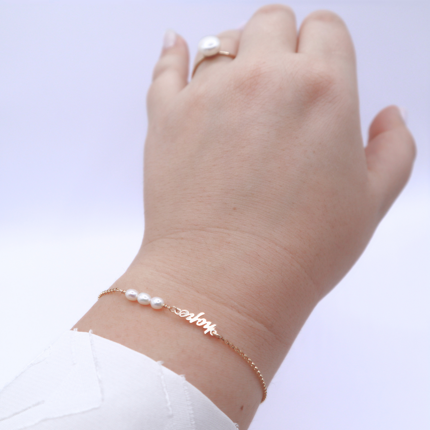 a dainty chain adorned with three small rice pearls and the word "hope".
