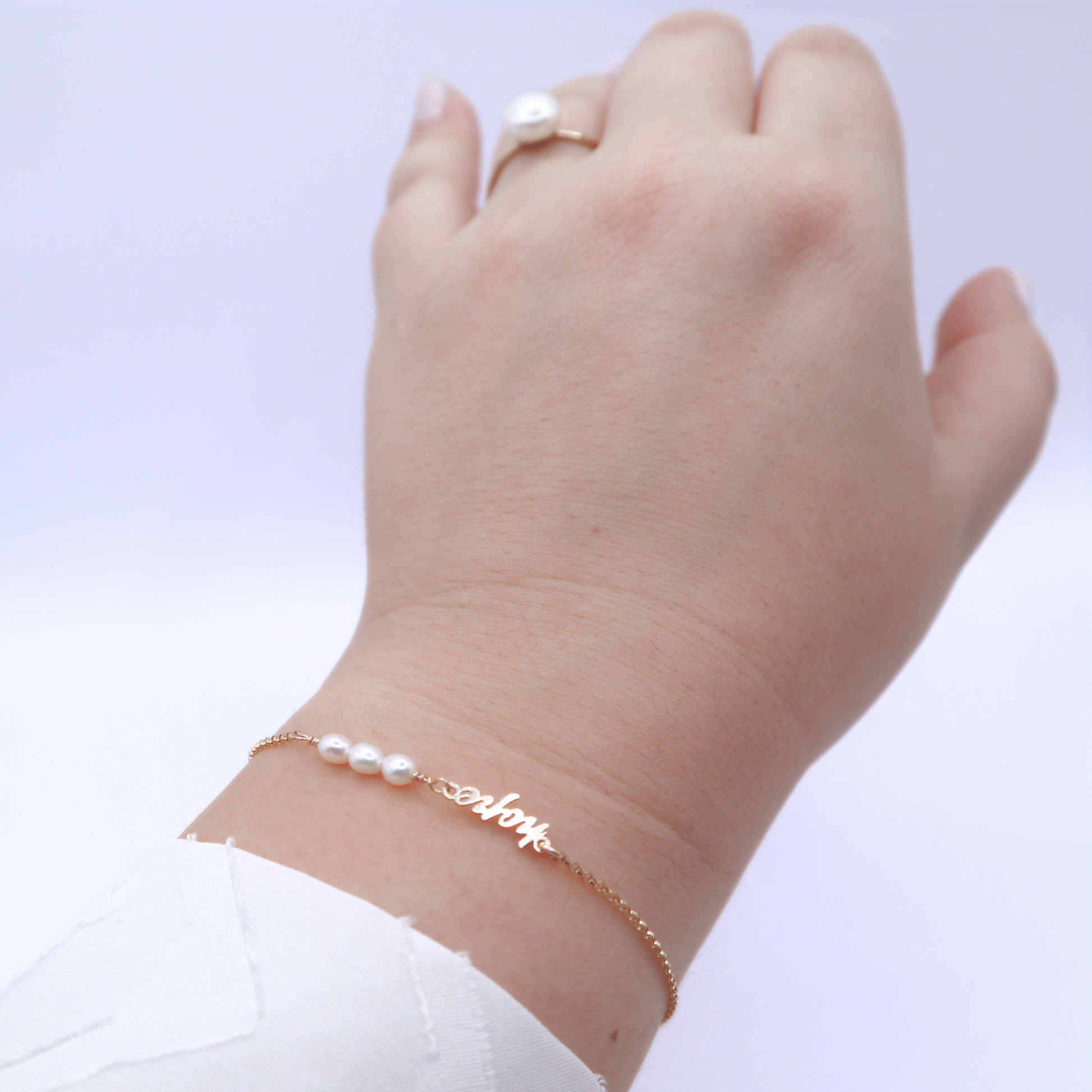 a dainty chain adorned with three small rice pearls and the word "hope".