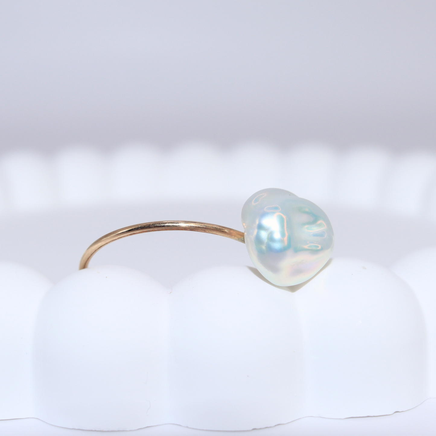 A beautiful baroque pearl gracefully perched on a gleaming gold ring, symbolizing elegance and refined taste.