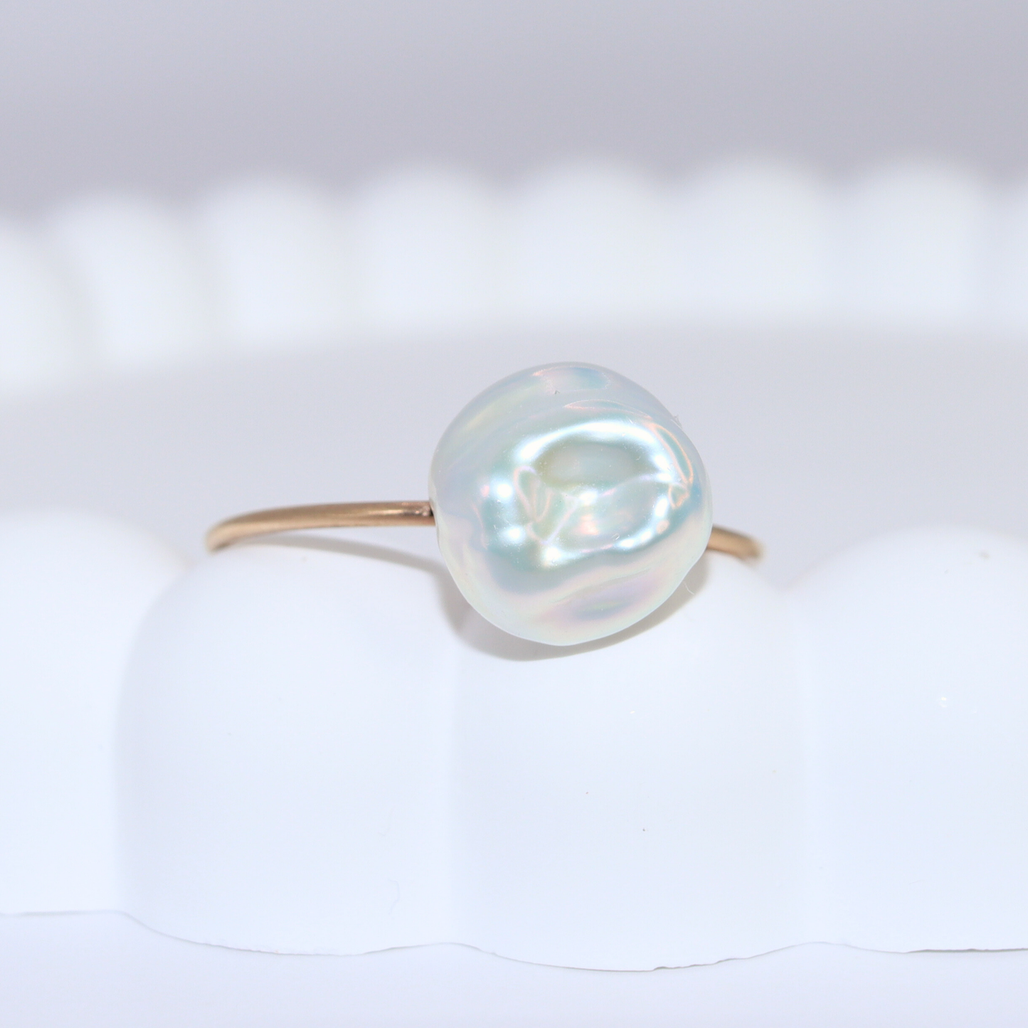 A beautiful baroque pearl gracefully perched on a gleaming gold ring, symbolizing elegance and refined taste.