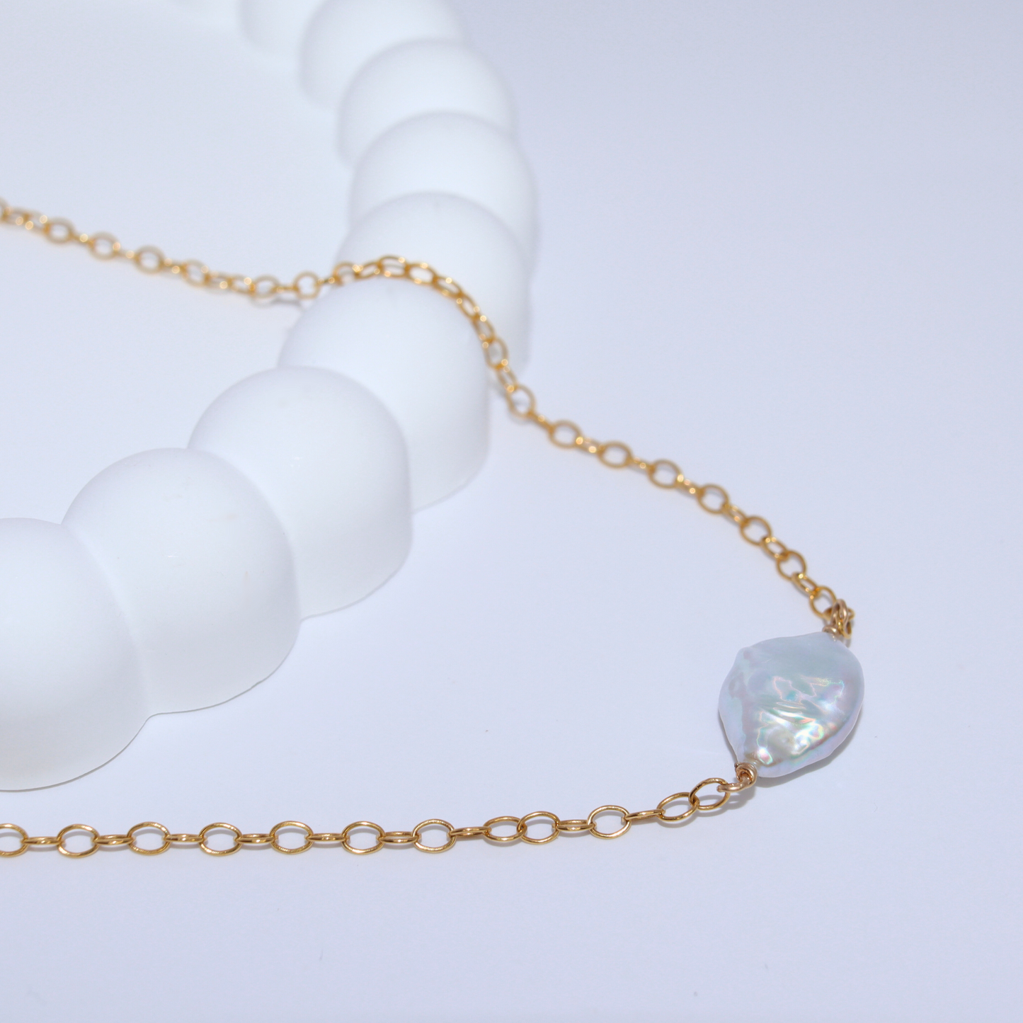 A delicate necklace featuring a baroque pearl elegantly suspended on a gold chain, showcasing timeless beauty.