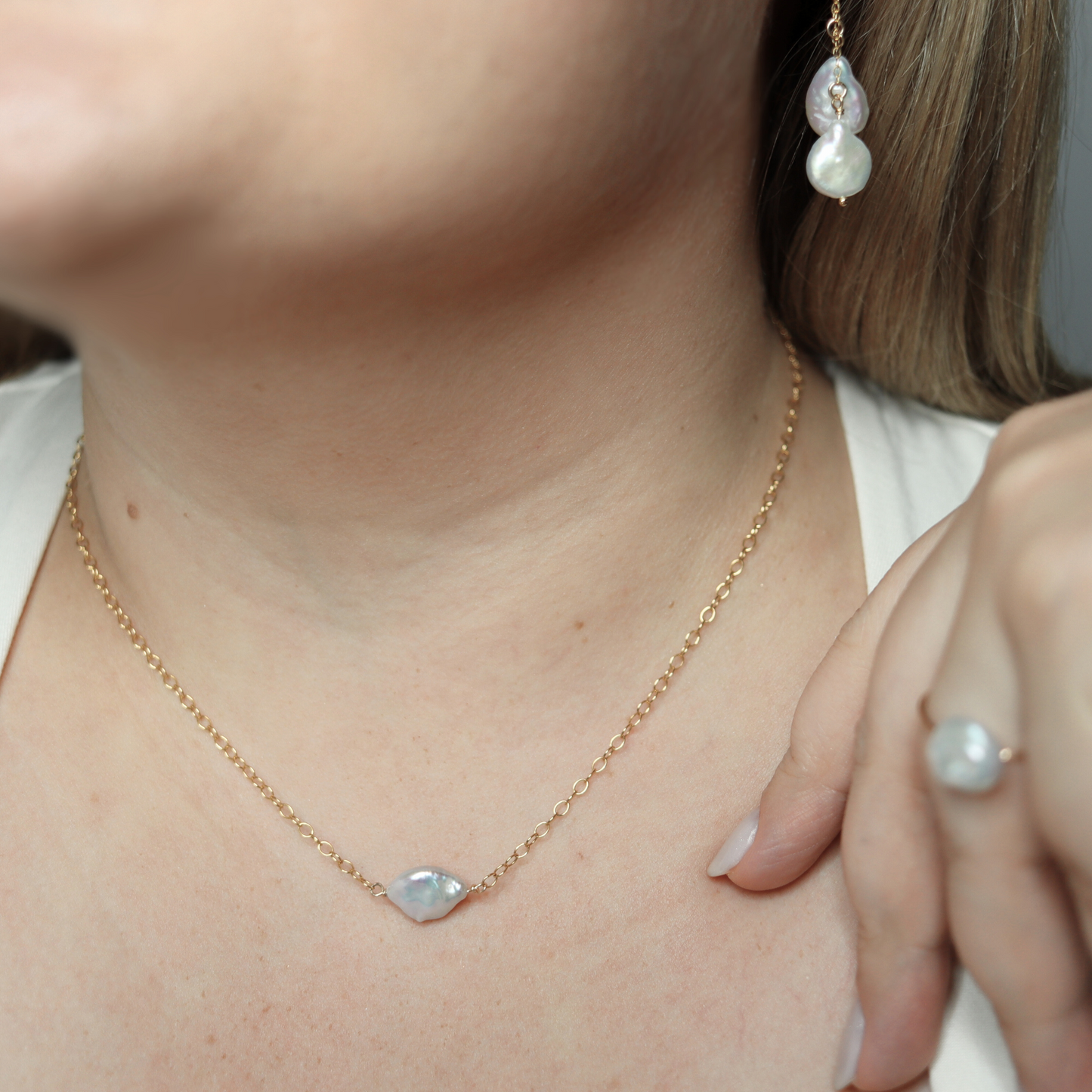 A delicate pearl necklace featuring a baroque pearl elegantly suspended on a gold chain, showcasing timeless beauty.