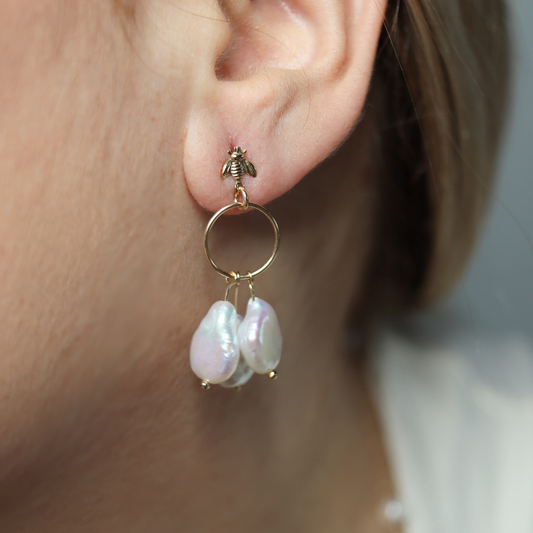 These stunning drop earrings feature a delicate dreamcatcher design, adorned with a bee stud and three luxurious baroque pearls.