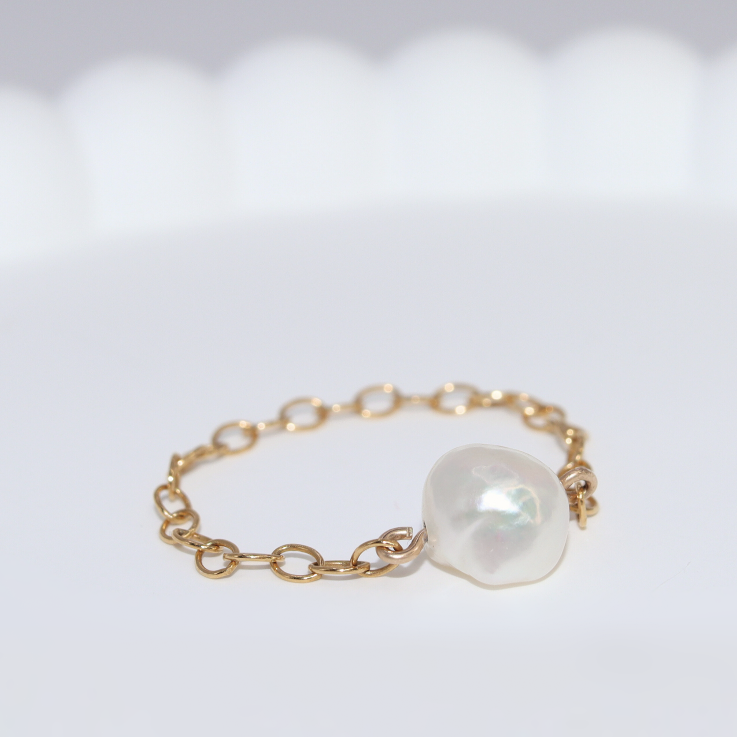 A stunning pearl ring featuring a delicate gold chain, embodying grace in every detail.