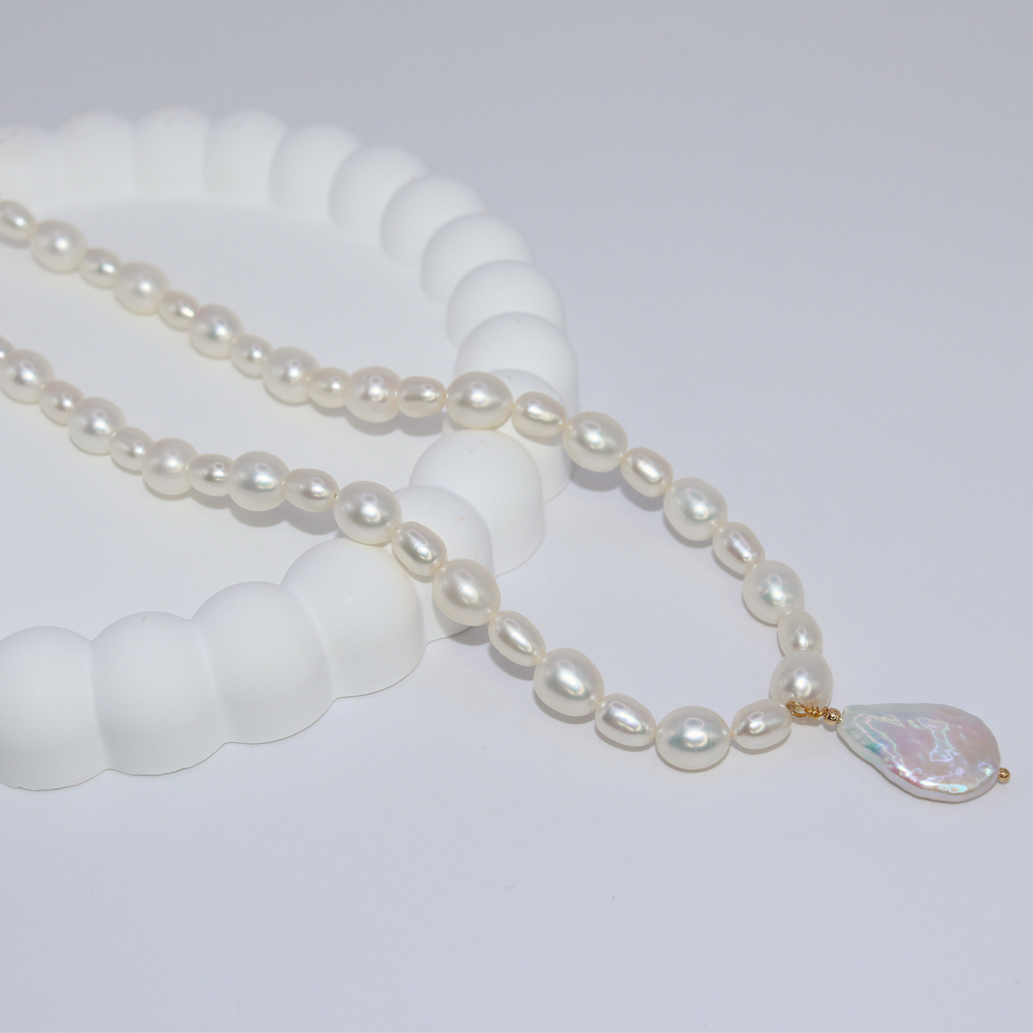 A stunning white pearl necklace adorned with a teardrop pearl pendant, exemplifying elegance and classic style.