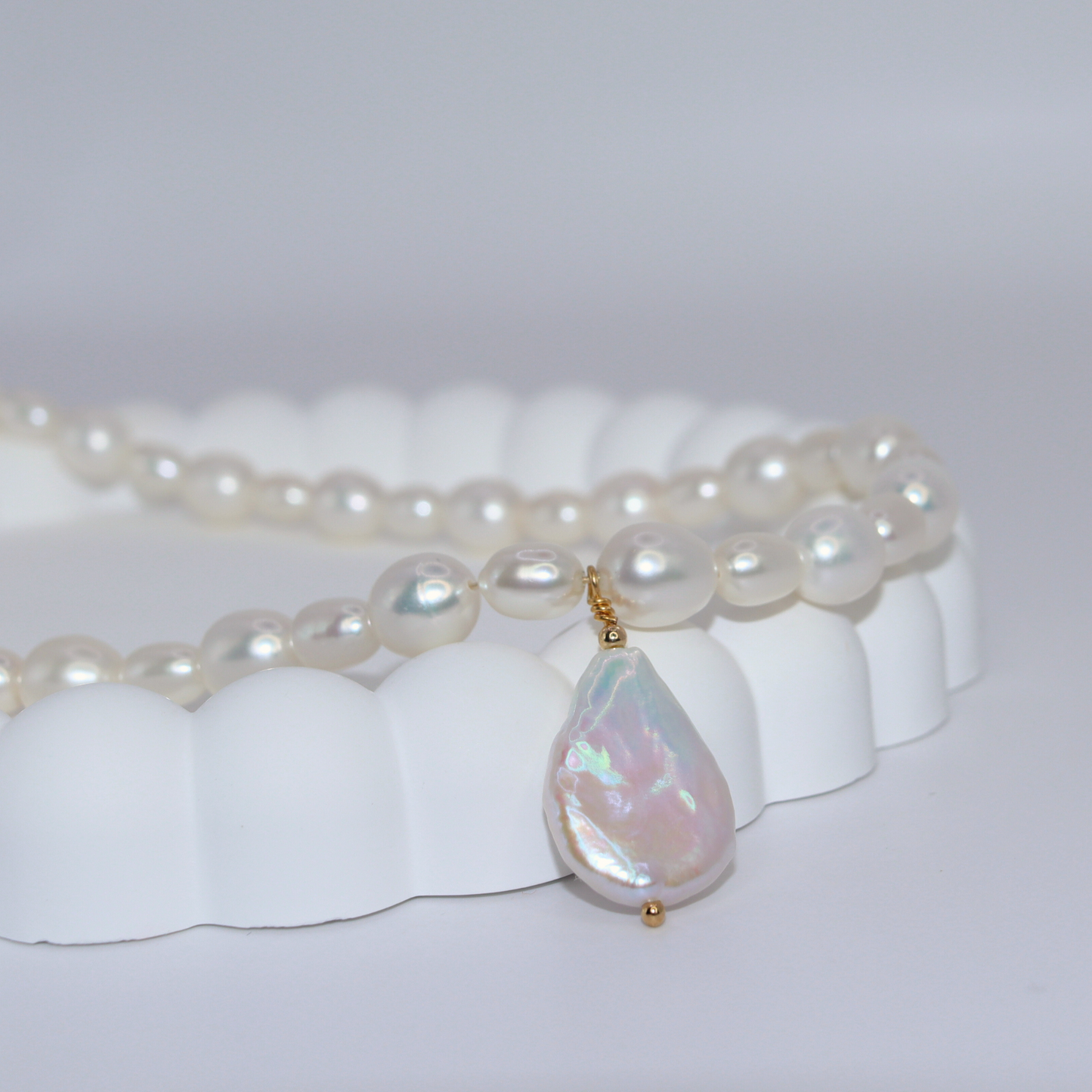 A stunning white pearl necklace adorned with a teardrop pearl pendant, exemplifying elegance and classic style.