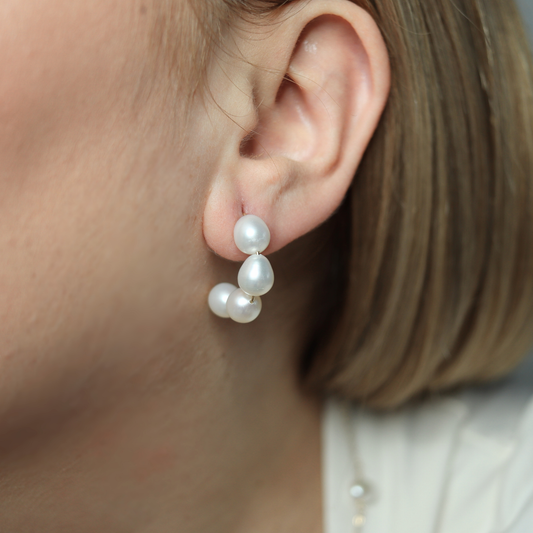 The delicate stud half hoop design is complemented by large rice pearls, creating a sophisticated and exclusive look.