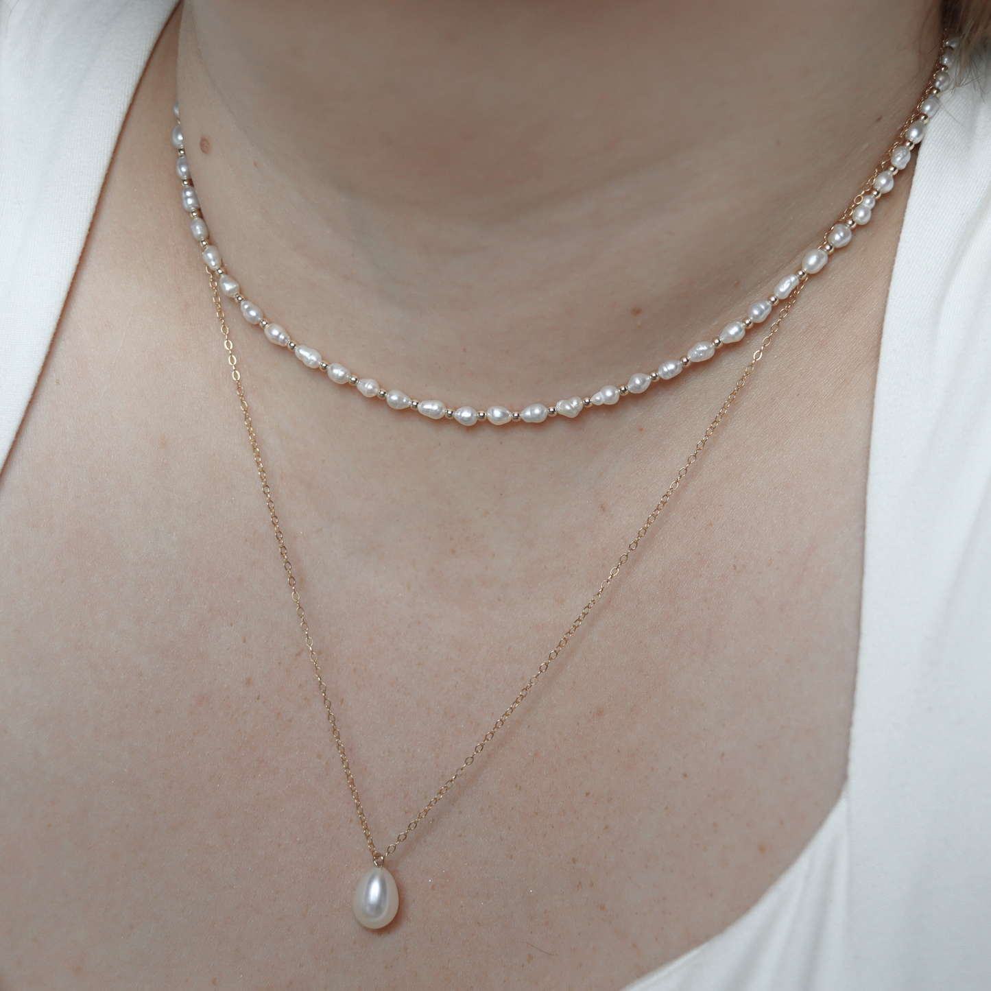 A stunning white teardrop pearl necklace complemented by a gleaming gold chain, embodying elegance and classic style.