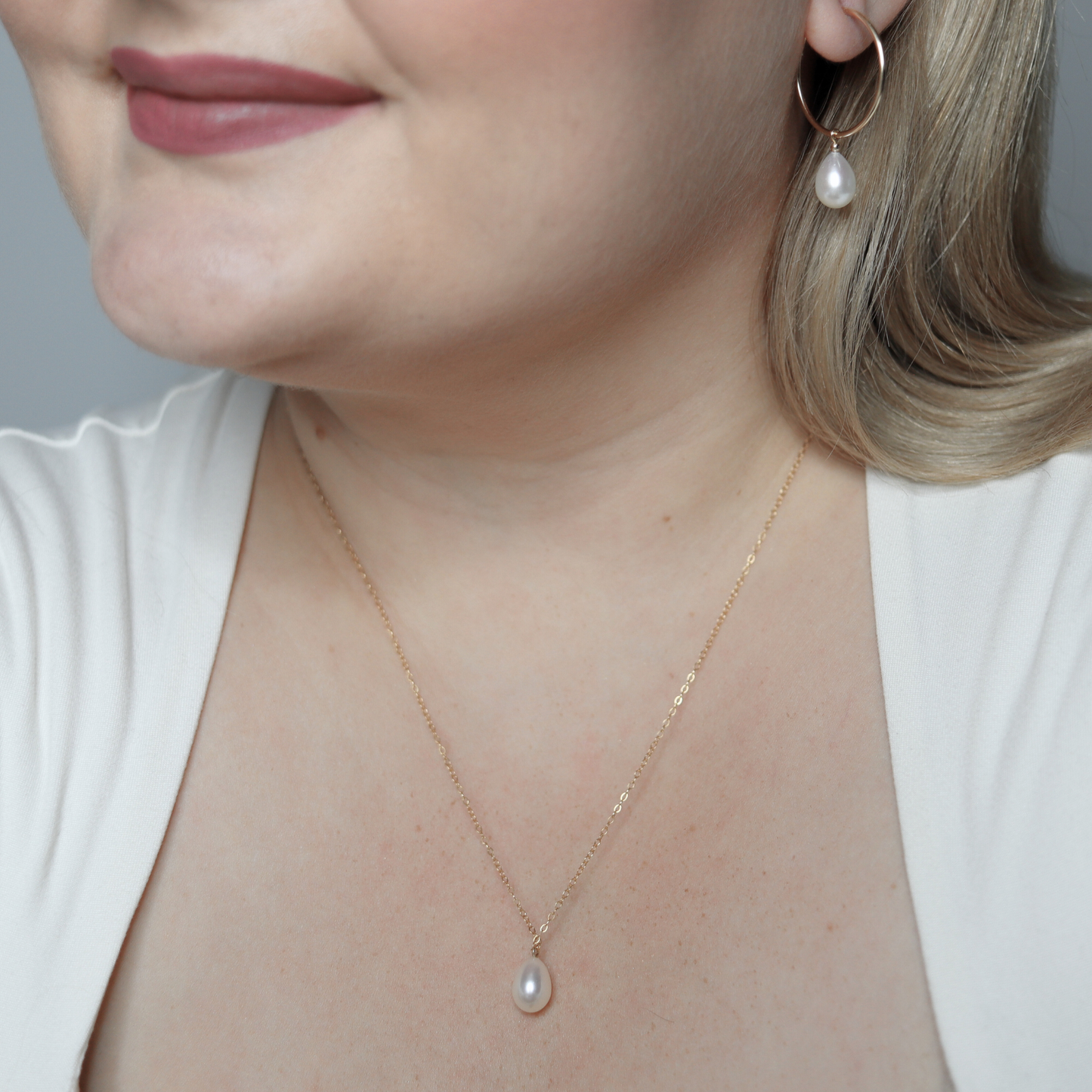 A stunning white teardrop pearl necklace complemented by a gleaming gold chain, embodying elegance and classic style.