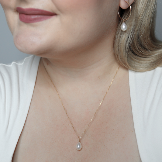 A stunning white teardrop pearl necklace complemented by a gleaming gold chain, embodying elegance and classic style.