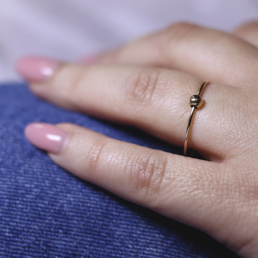 A stunning gold ring with a charming small ball, radiating opulence and grace in its minimalist design.