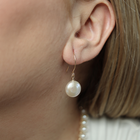 These exquisite earrings feature lustrous coin pearls delicately suspended from round hook earrings.