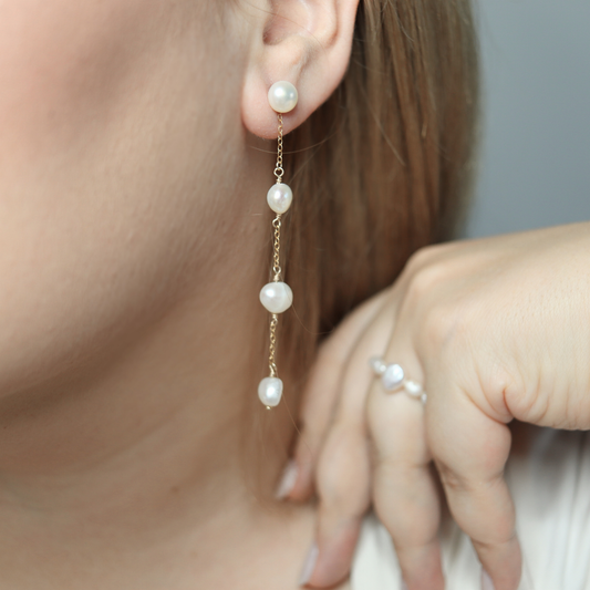 These elegant earrings feature a stud pearl and a delicate chain adorned with three lustrous baroque pearls.