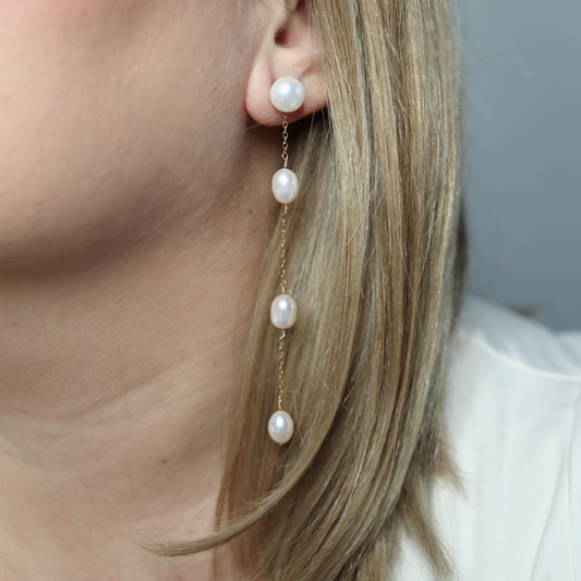 These elegant earrings feature a stud pearl connected to a delicate chain adorned with three rice pearls, creating a beautiful and unique look.