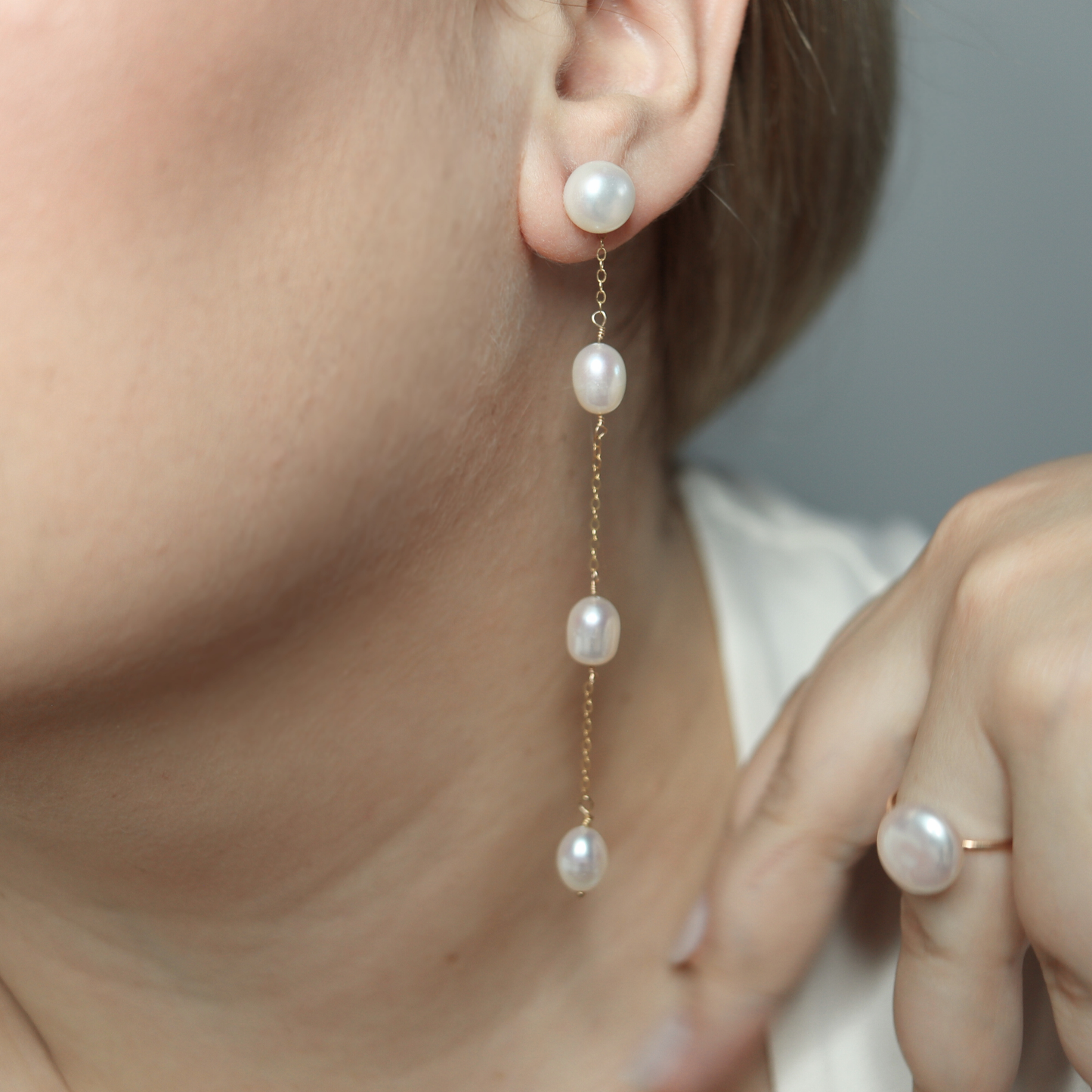 These elegant earrings feature a stud pearl connected to a delicate chain adorned with three rice pearls, creating a beautiful and unique look.