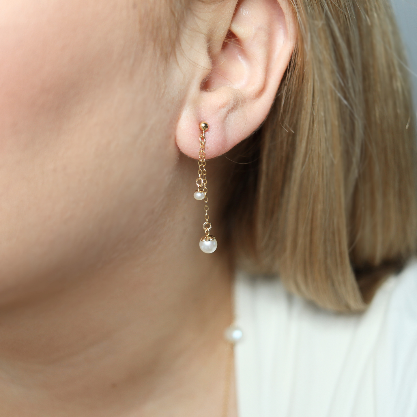 Made with two small pearls delicately dangling on dainty chains, these ball stud earrings add a touch of sophistication to any outfit.