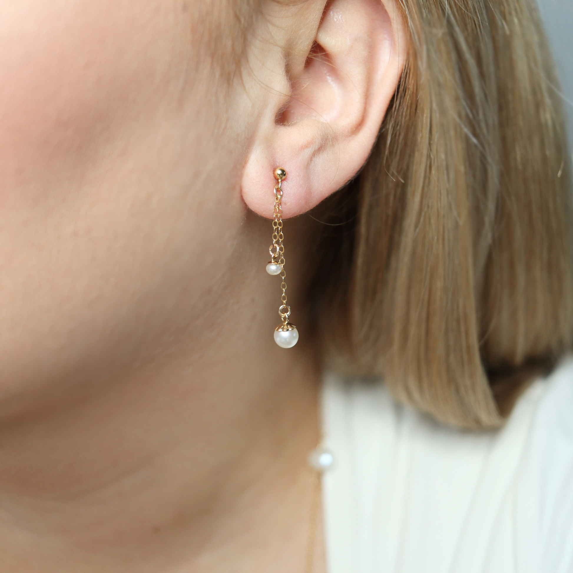 Made with two small pearls delicately dangling on dainty chains, these ball stud earrings add a touch of sophistication to any outfit.