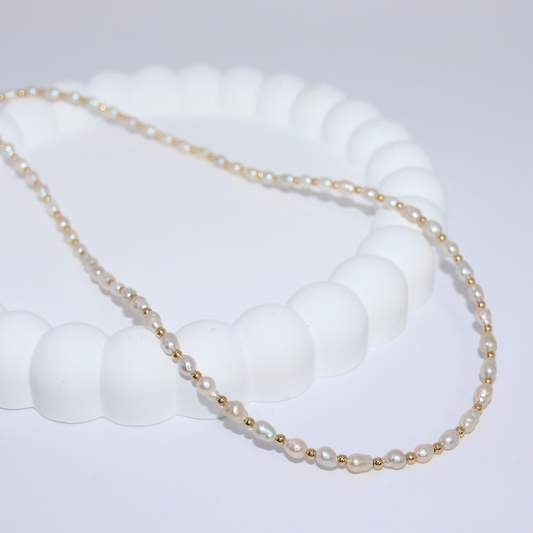 An elegant gold beads and tiny ivory pearls necklace, featuring a harmonious blend of colors and a sophisticated design.