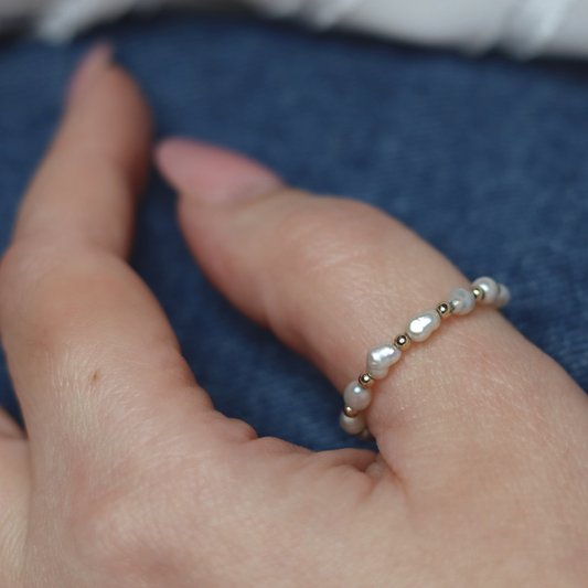 A luxurious white pearl ring embellished with radiant gold beads, perfect for adding a touch of elegance to any ensemble.