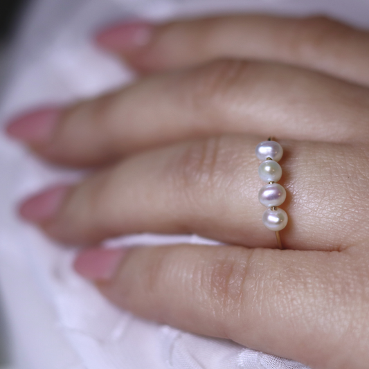 A stunning white pearl ring featuring four exquisite pearls set on a luxurious gold band, radiating elegance and sophistication.