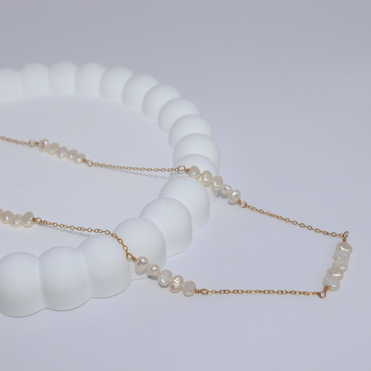 A delicate chain necklace featuring clusters of four small, lustrous pearls elegantly arranged along its length.