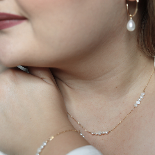 A delicate chain necklace featuring clusters of four small, lustrous pearls elegantly arranged along its length.