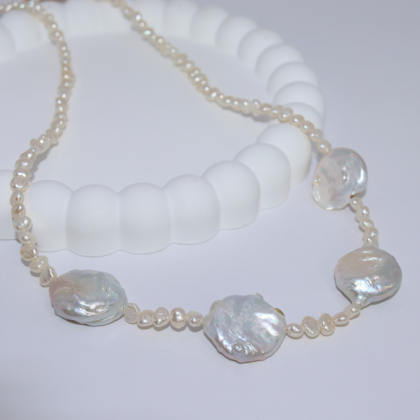 An exquisite white pearl necklace adorned with seed pearls and four prominent baroque pearls, showcasing refined elegance.