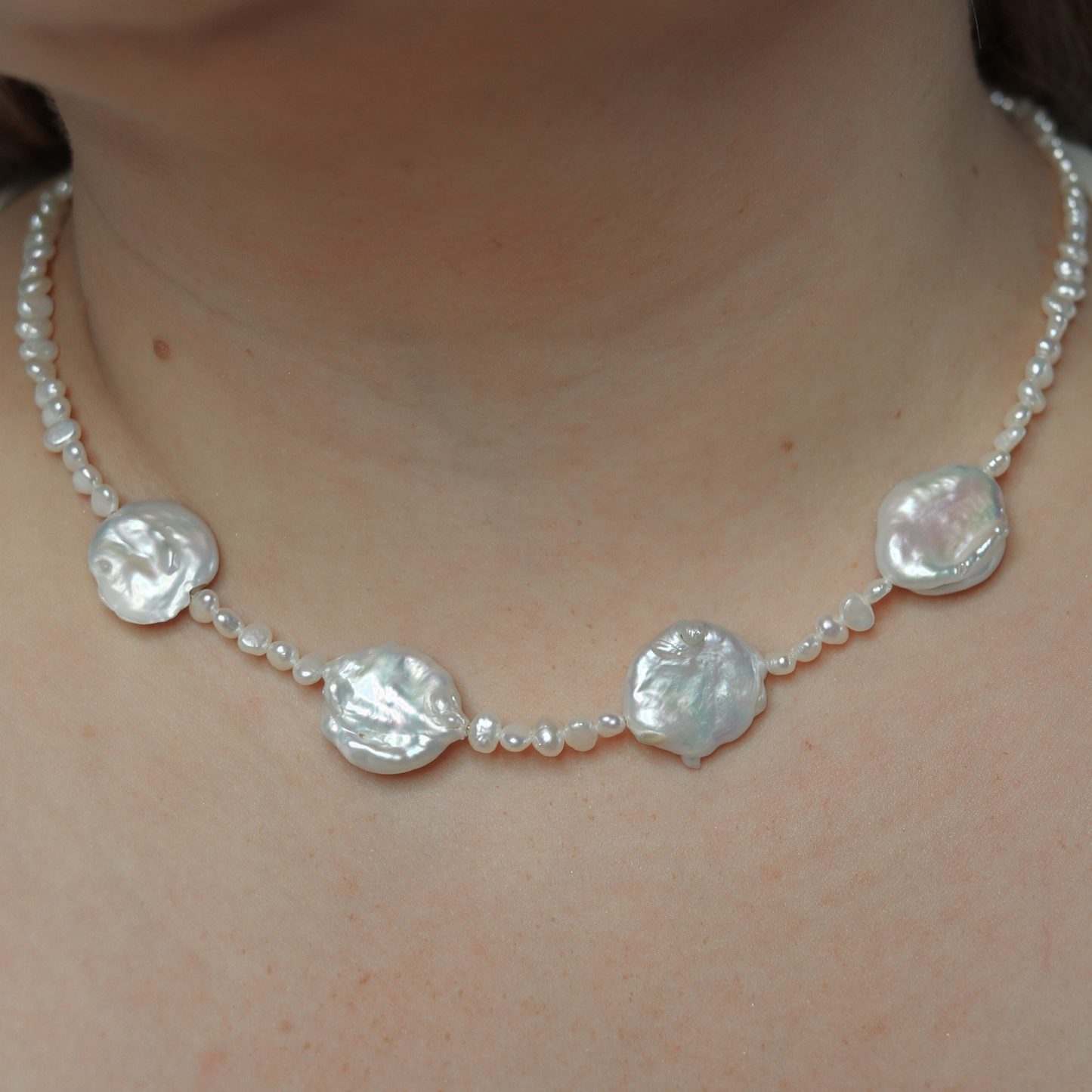 An exquisite white pearl necklace adorned with seed pearls and four prominent baroque pearls, showcasing refined elegance.