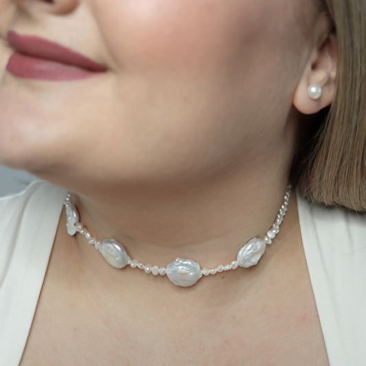 An exquisite white pearl necklace adorned with seed pearls and four prominent baroque pearls, showcasing refined elegance.