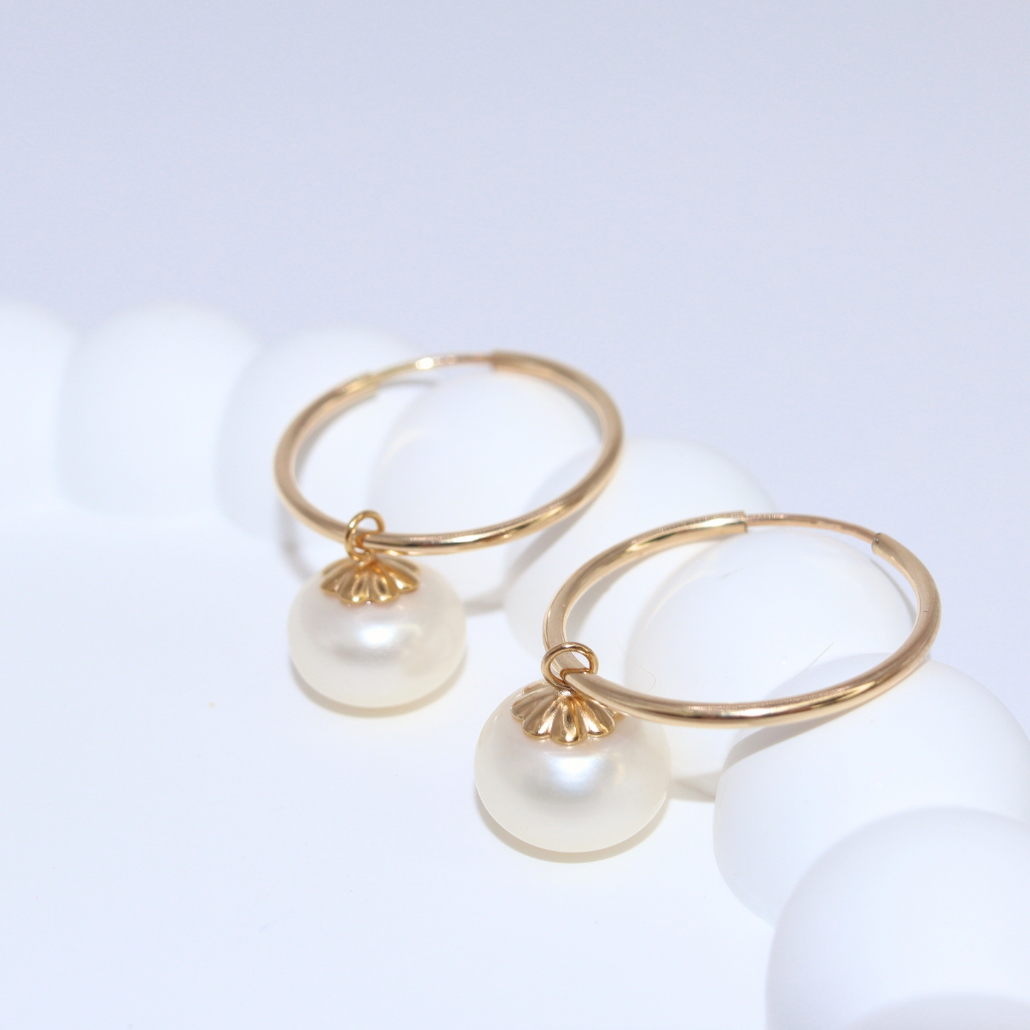 Elevate your look with our Zoe Pearl Hoop Earrings, featuring a solitaire pearl delicately perched on a sleek hoop