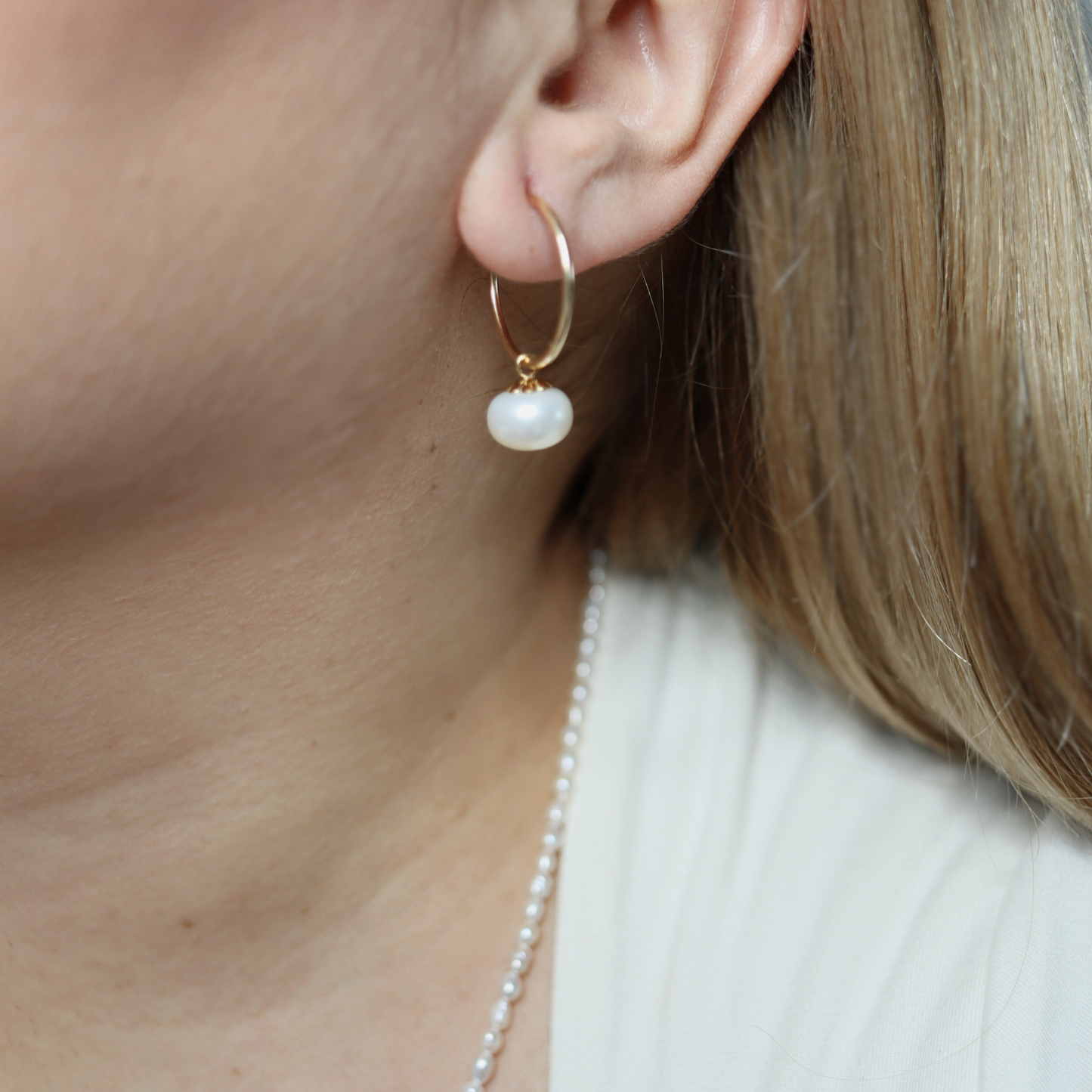 Elevate your look with our Zoe Pearl Hoop Earrings, featuring a solitaire pearl delicately perched on a sleek hoop
