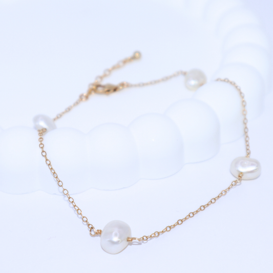 A stunning baroque pearl bracelet featured on a gold chain, emphasizing the elegance of the pearls against the gold backdrop.