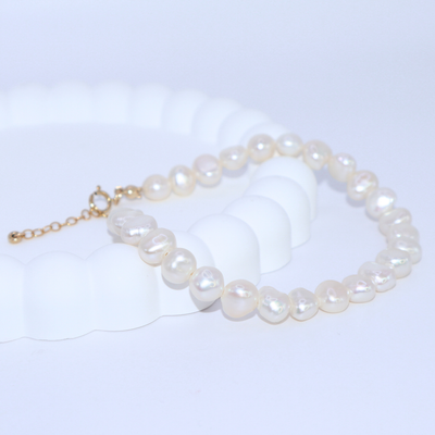 A stylish white baroque pearl bracelet adorned with a gold extension chain, highlighting a refined and contemporary aesthetic.