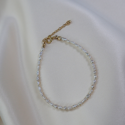 Delicate seed pearl beaded bracelet on a white fabric background