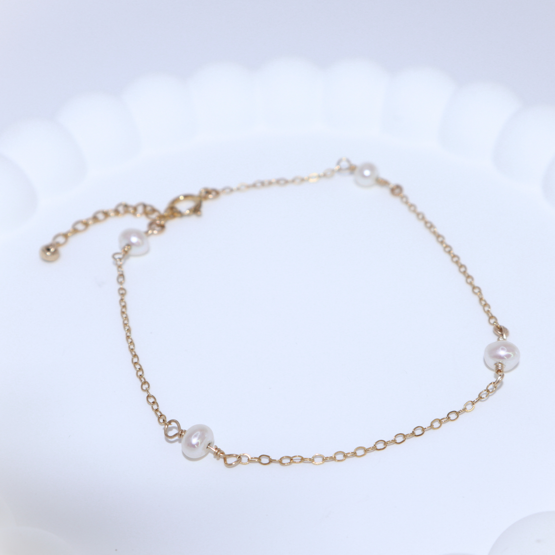 A gold chain bracelet adorned with four elegant pearls, showcasing a blend of luxury and sophistication.