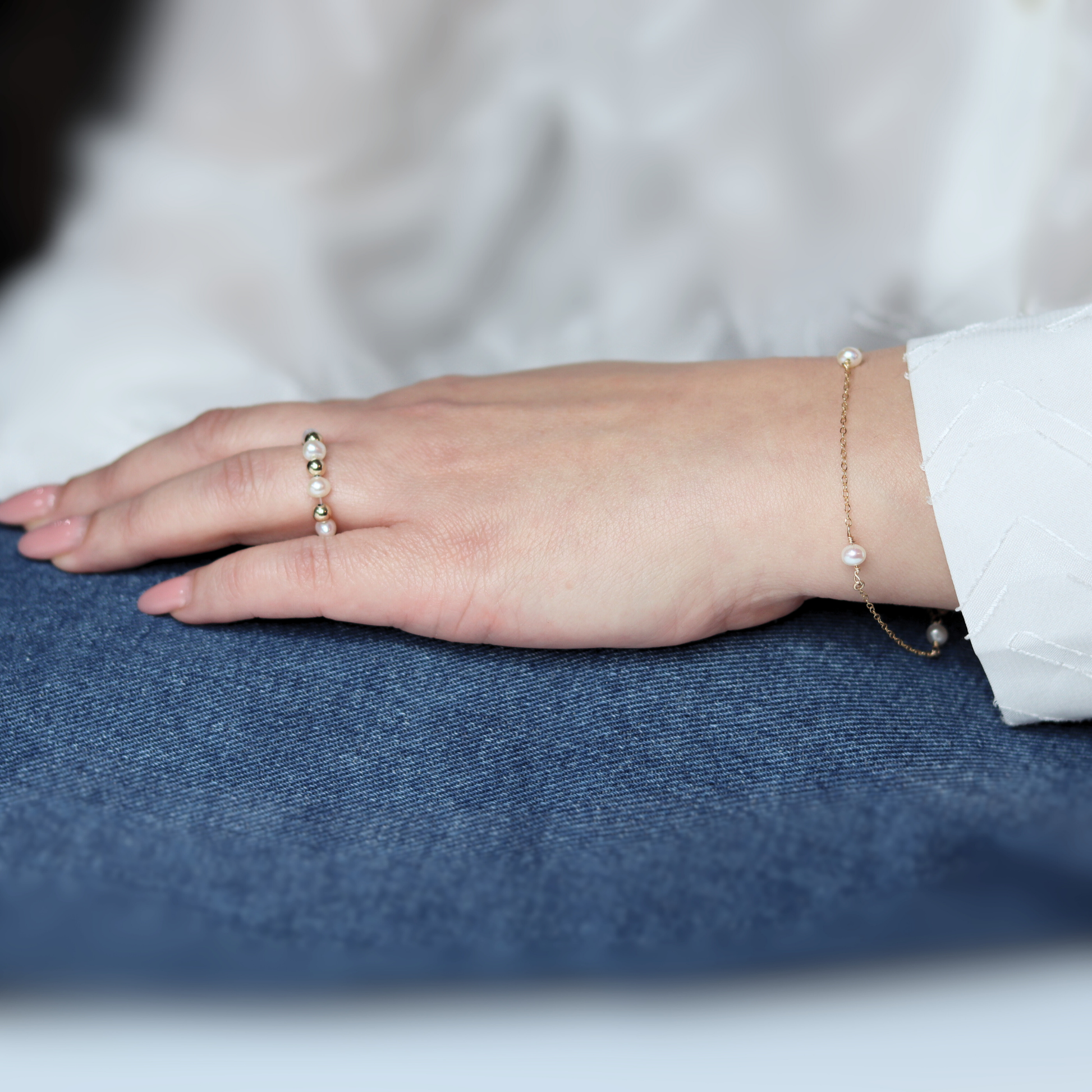 A gold chain bracelet adorned with four elegant pearls, showcasing a blend of luxury and sophistication.